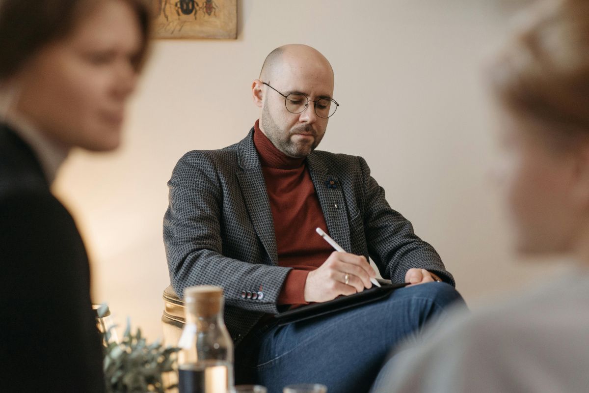 Psychotherapeut Symbolfoto Ein Foto von einem Psychotherapeuten mit zwei Klienten