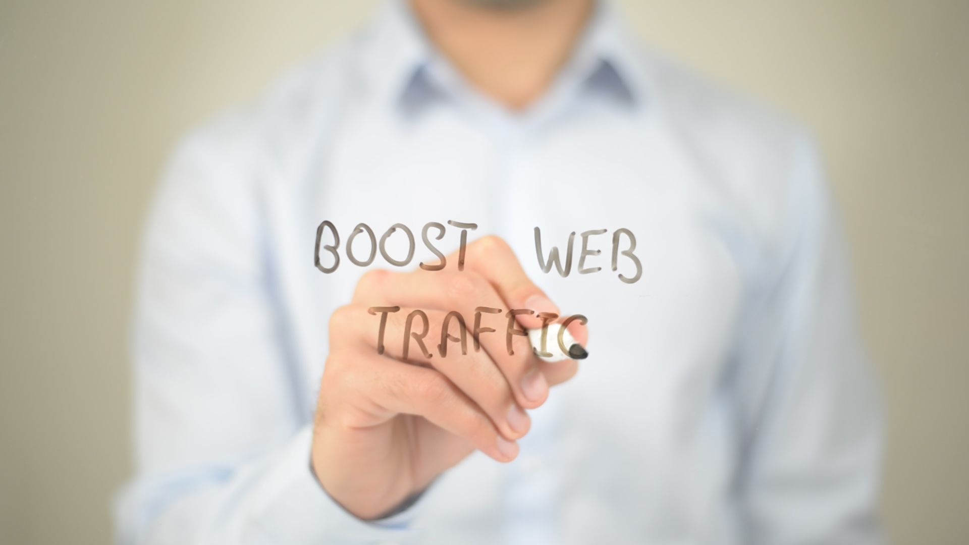 Ein Mann mit einem Stift, der auf einer transparenten Tafel die Worte 'Boost Web Traffic' schreibt.