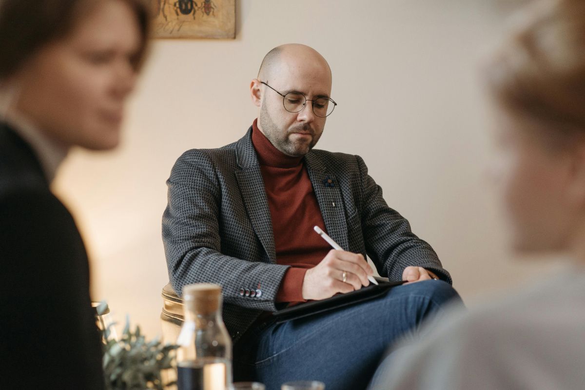 Ein Foto von einem Psychotherapeuten mit zwei Klienten