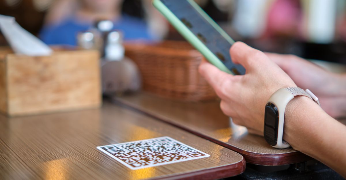 Eine Person scannt im Restaurant einen QR Code, um die digitale Speisekarte auf dem Smartphone zu öffnen.