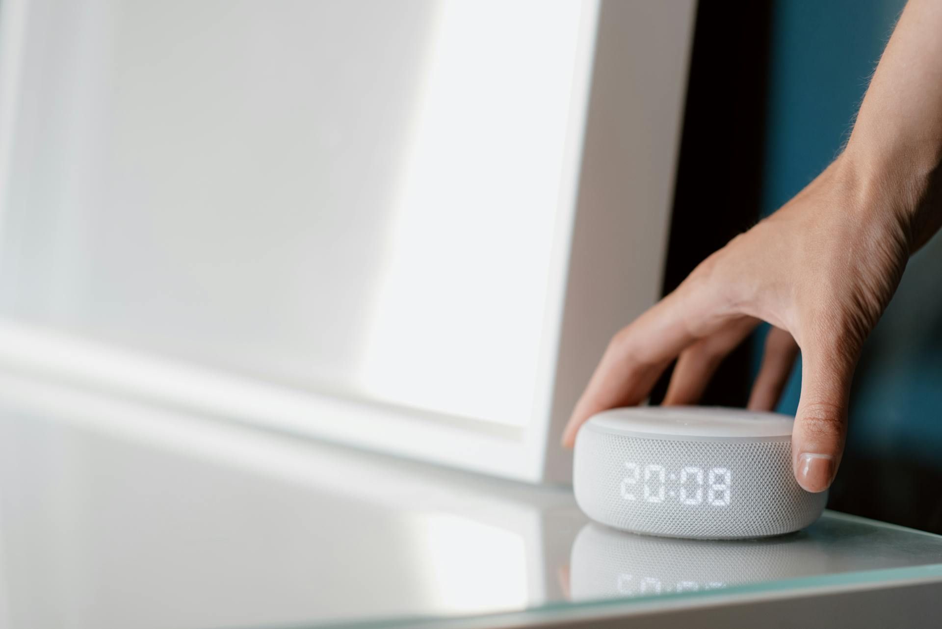 Eine Hand, die von oben auf das Amazon Echo Gerät greift